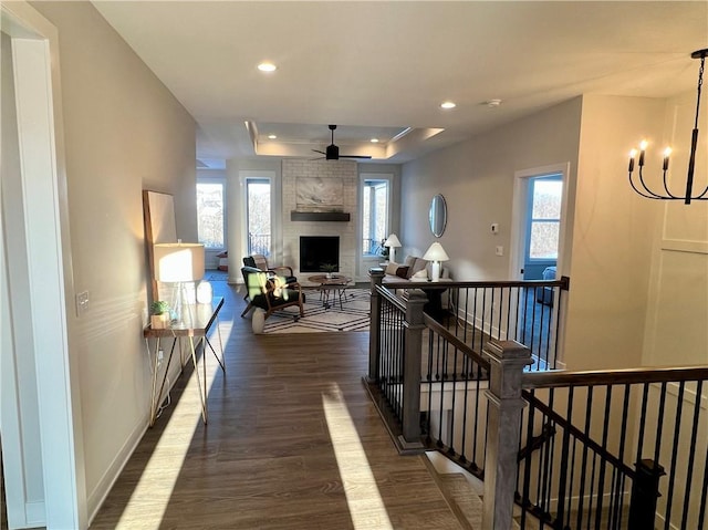 corridor featuring a tray ceiling, dark hardwood / wood-style floors, and a notable chandelier