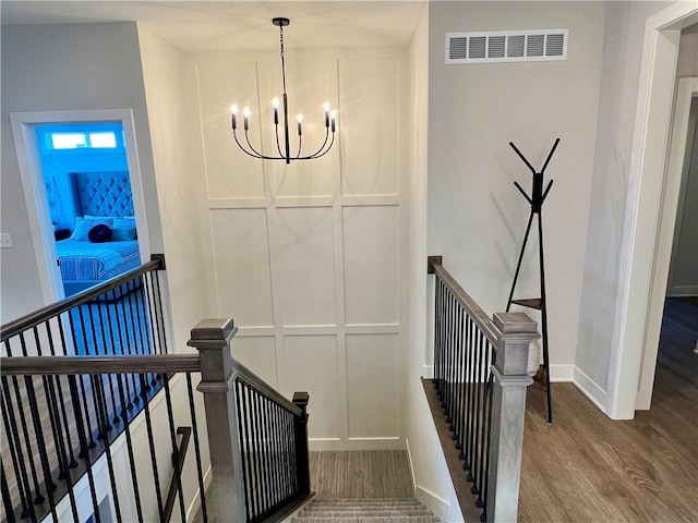 staircase with hardwood / wood-style flooring and a chandelier