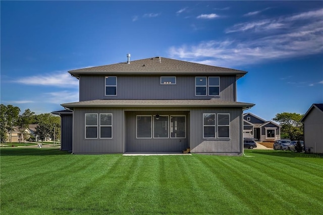 back of property with a yard, a patio, and roof with shingles