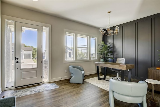 interior space featuring a chandelier, a decorative wall, wood finished floors, and baseboards