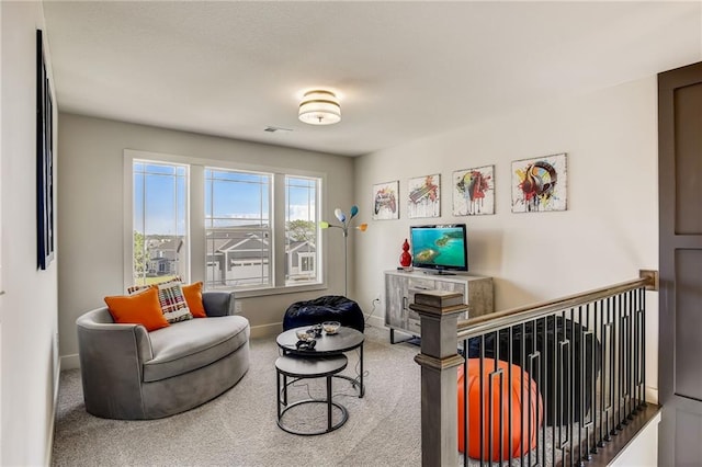 living area featuring carpet, visible vents, baseboards, and an upstairs landing