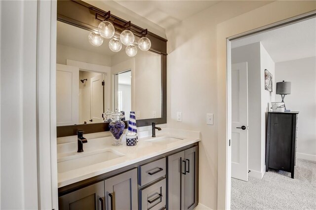 full bathroom with double vanity, a sink, and baseboards