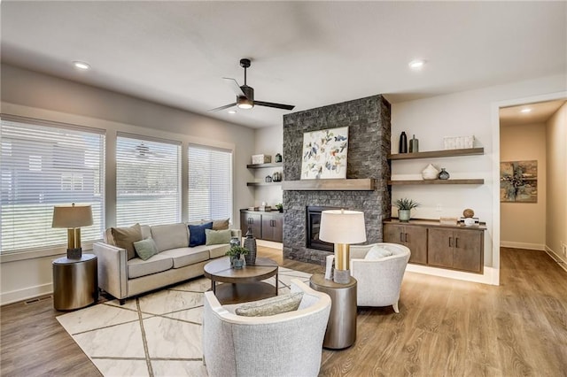 living area featuring light wood-style flooring, a fireplace, baseboards, and a wealth of natural light