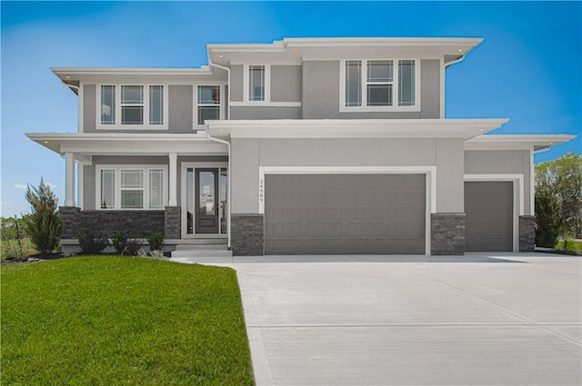 prairie-style home featuring driveway, stone siding, a front yard, and stucco siding