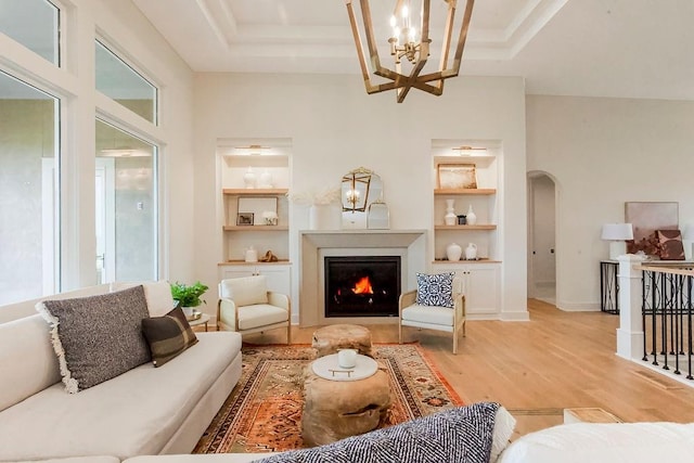 living room featuring light hardwood / wood-style flooring, built in features, and a notable chandelier