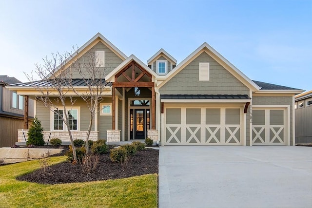 view of front of house with a garage, driveway, a standing seam roof, and metal roof