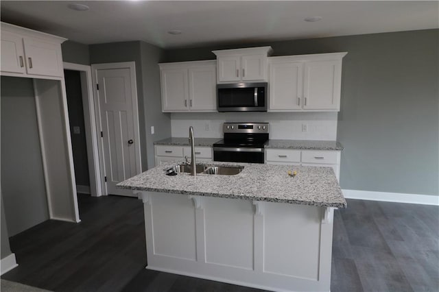 kitchen with white cabinetry, sink, light stone counters, a kitchen island with sink, and appliances with stainless steel finishes