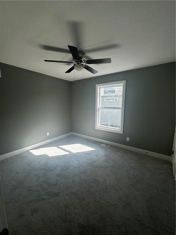 empty room with dark carpet and ceiling fan