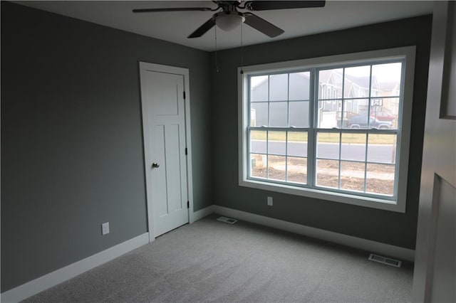 unfurnished room with ceiling fan, light colored carpet, and a wealth of natural light