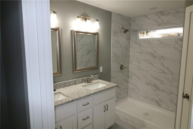 bathroom with a tile shower and vanity