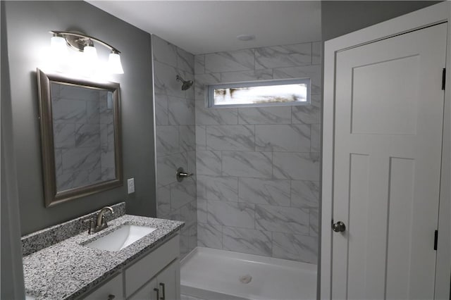 bathroom with tiled shower and vanity