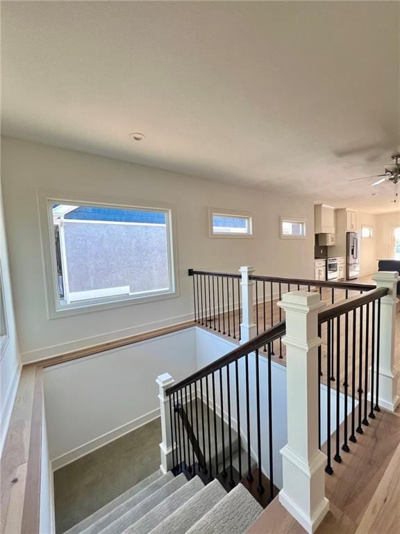 stairs featuring hardwood / wood-style flooring and ceiling fan