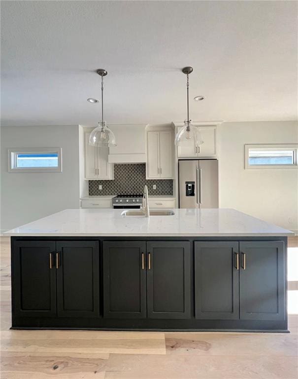 kitchen with appliances with stainless steel finishes, pendant lighting, white cabinetry, sink, and a spacious island