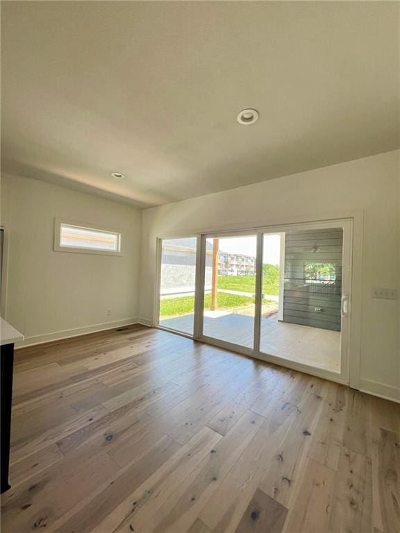 spare room with a wealth of natural light and wood-type flooring