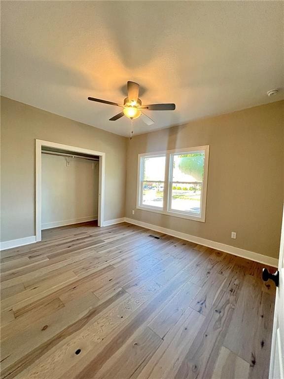 unfurnished bedroom with ceiling fan, light hardwood / wood-style floors, and a closet