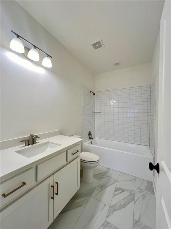 full bathroom featuring tiled shower / bath combo, vanity, and toilet