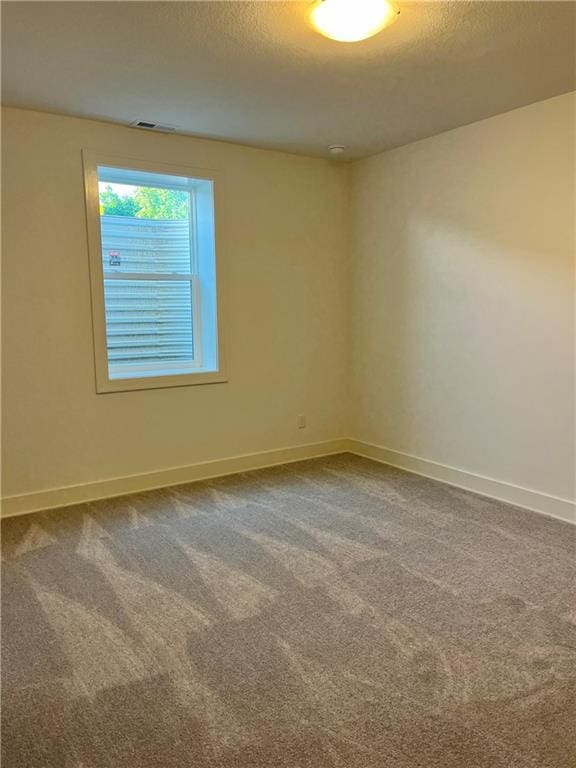 carpeted empty room featuring a textured ceiling