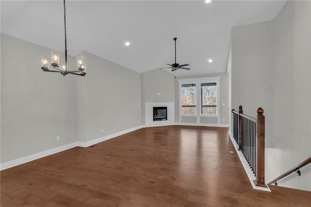 unfurnished living room with vaulted ceiling, dark wood-type flooring, and ceiling fan with notable chandelier