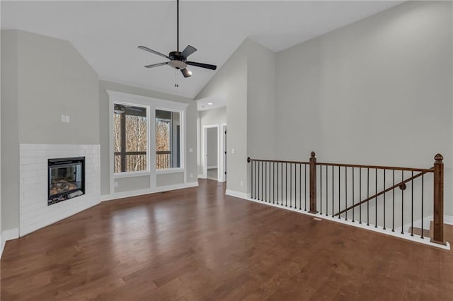 unfurnished living room featuring a brick fireplace, dark wood-type flooring, lofted ceiling, and ceiling fan