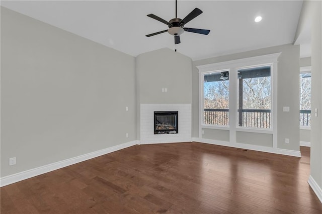 unfurnished living room featuring ceiling fan, vaulted ceiling, a fireplace, and dark hardwood / wood-style flooring