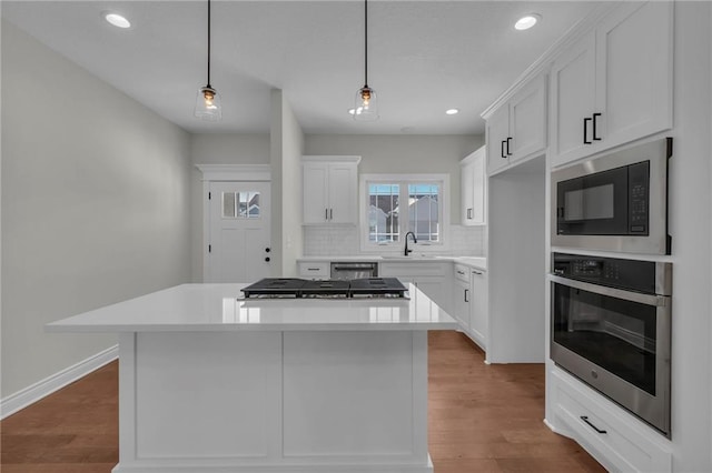 kitchen featuring appliances with stainless steel finishes, a kitchen island, white cabinetry, and pendant lighting