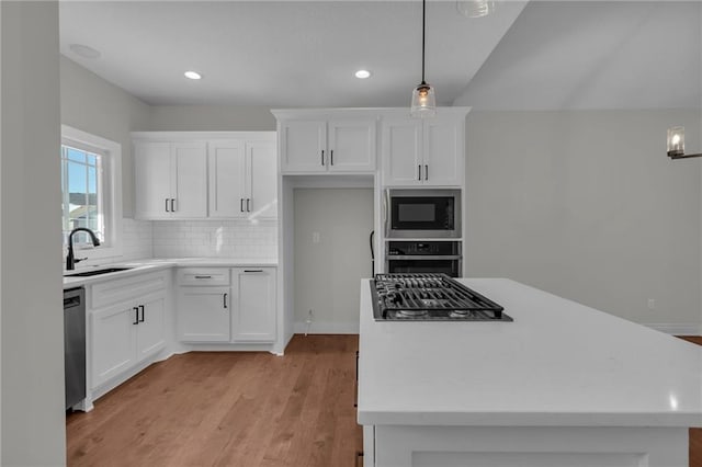 kitchen with stainless steel appliances, sink, white cabinets, and decorative light fixtures