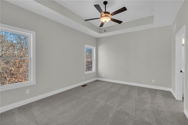 unfurnished room featuring ceiling fan, a raised ceiling, and carpet flooring