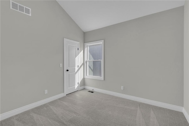 spare room with vaulted ceiling and light colored carpet