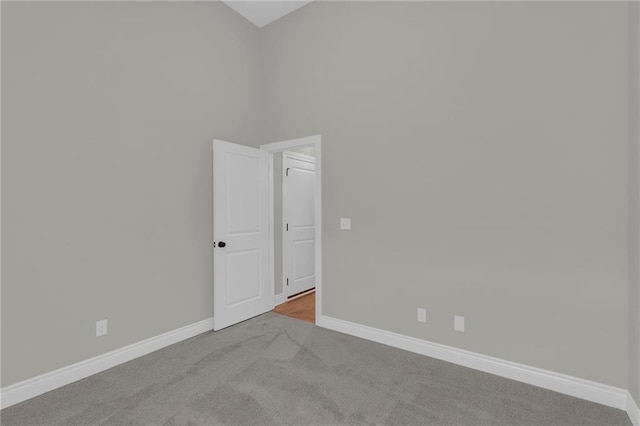 carpeted spare room featuring a high ceiling