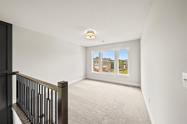 spare room with a textured ceiling and carpet