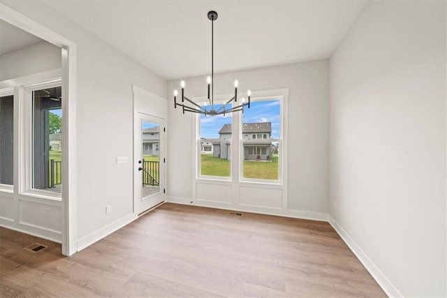 unfurnished dining area featuring light wood-type flooring and an inviting chandelier