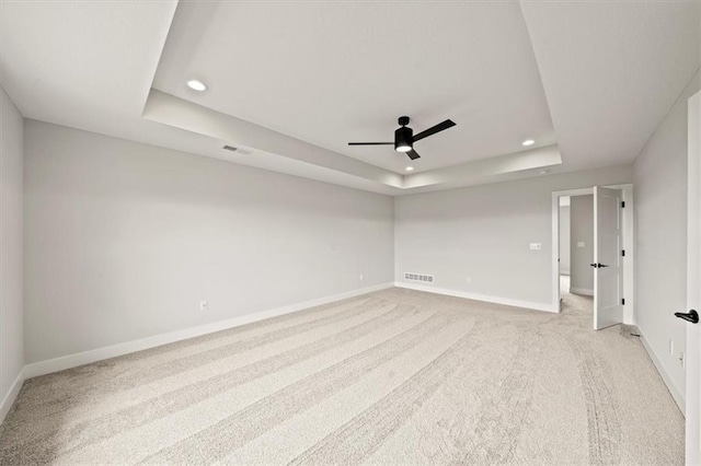 carpeted spare room featuring ceiling fan and a tray ceiling