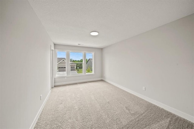 carpeted empty room featuring a textured ceiling