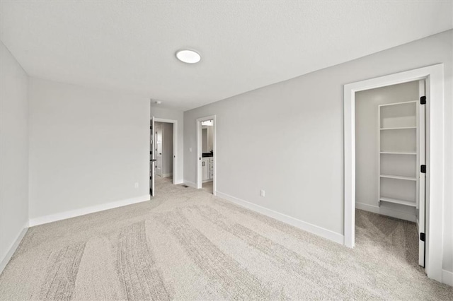 unfurnished bedroom featuring a spacious closet, a closet, and light carpet