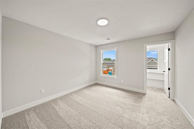 carpeted empty room with a textured ceiling