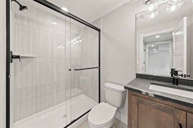 bathroom featuring toilet, vanity, and a shower with door