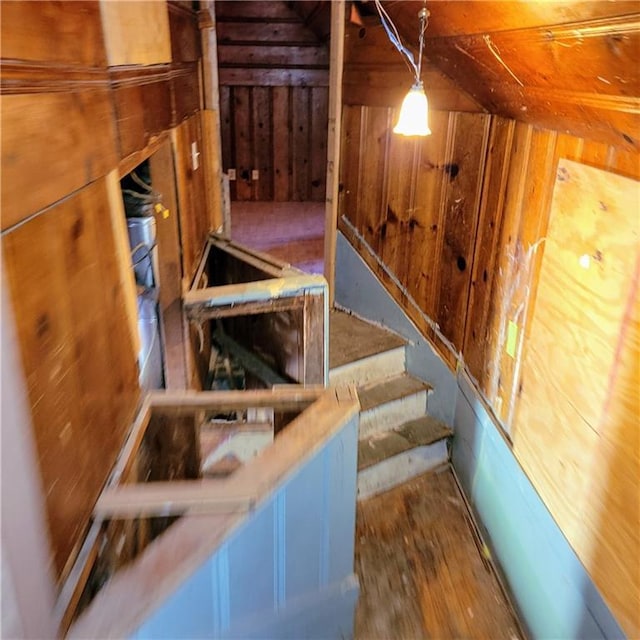 stairs featuring wood-type flooring, lofted ceiling, and wooden walls