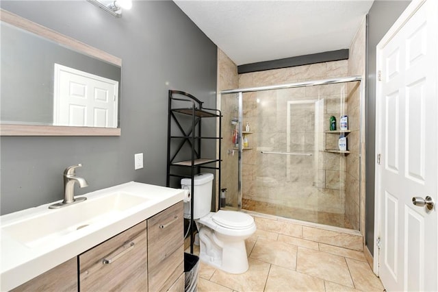 bathroom with a shower with shower door, tile flooring, vanity, and toilet