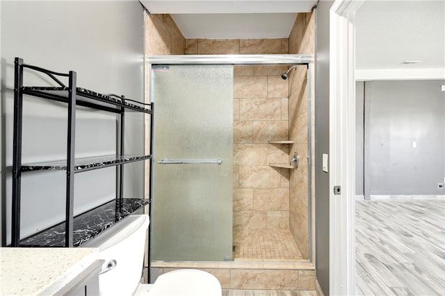 bathroom featuring a shower with shower door, vanity, and toilet