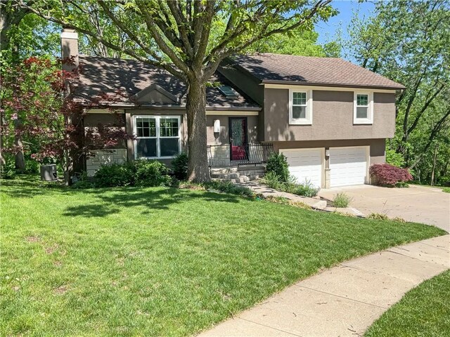 tri-level home featuring a garage and a front lawn