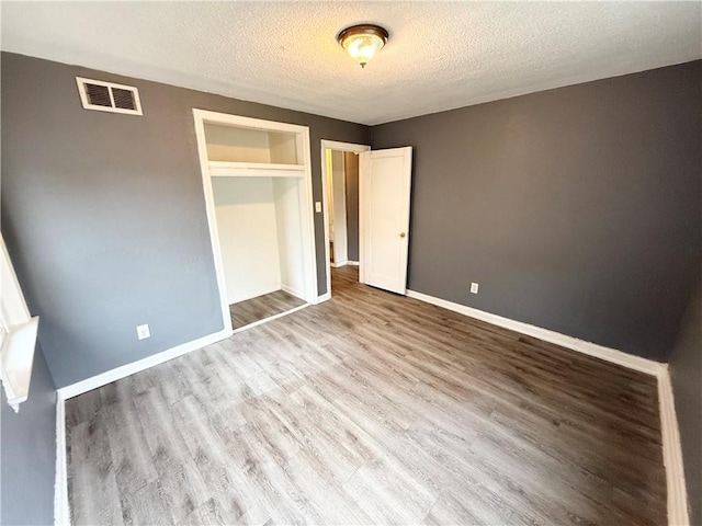 unfurnished bedroom with a closet, light wood-type flooring, and a textured ceiling