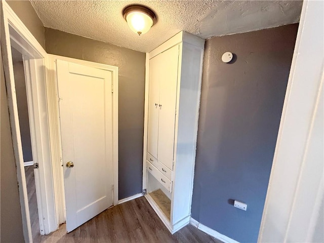 corridor featuring dark wood-type flooring and a textured ceiling