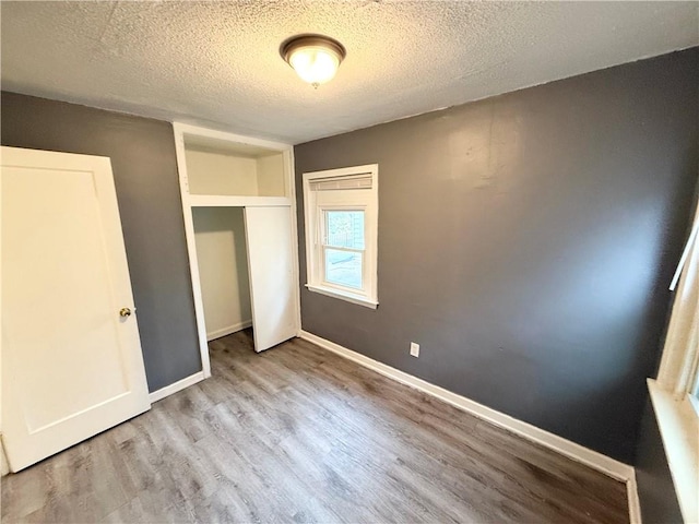 unfurnished bedroom featuring a closet, a textured ceiling, and light hardwood / wood-style flooring