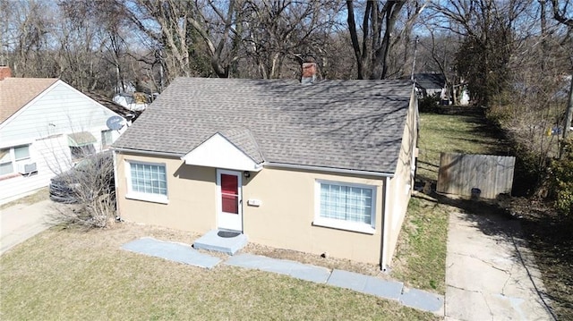 6133 Walrond Ave, Kansas City, MO 64130 - view of front of home featuring stucco siding, a front yard, and a shingled roof
