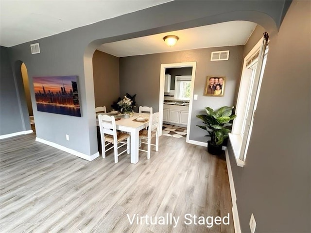 6133 Walrond Ave, Kansas City, MO 64130 - dining space featuring visible vents, arched walkways, baseboards, and wood finished floors