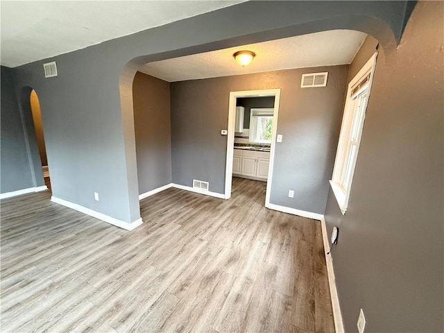 6133 Walrond Ave, Kansas City, MO 64130 - spare room with wood finished floors, visible vents, arched walkways, and baseboards