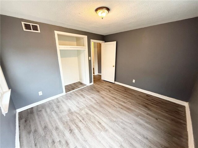6133 Walrond Ave, Kansas City, MO 64130 - unfurnished bedroom featuring baseboards, wood finished floors, visible vents, and a textured ceiling