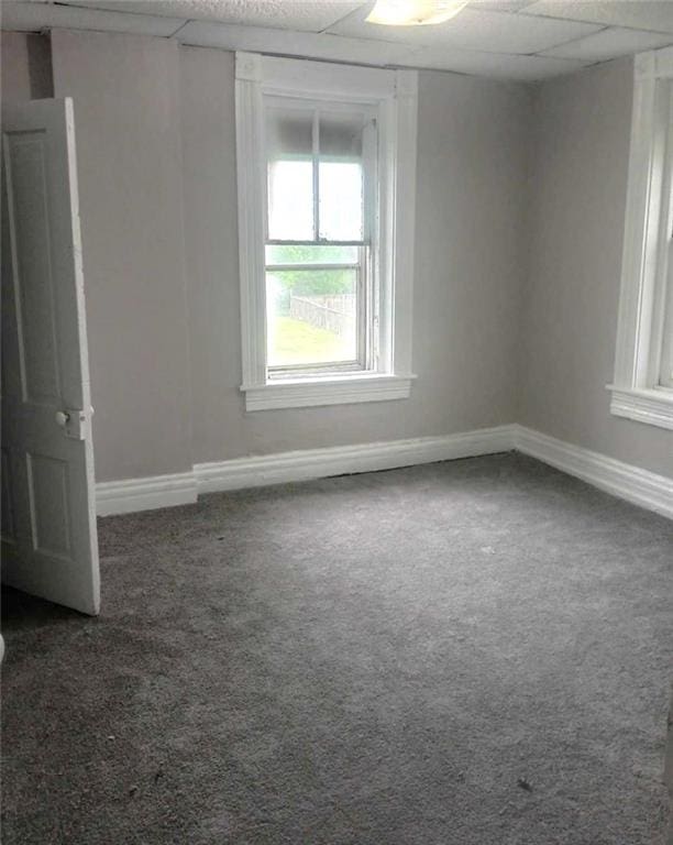 carpeted empty room with a drop ceiling