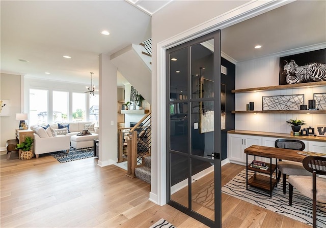 wine room featuring a notable chandelier, light wood-type flooring, and crown molding