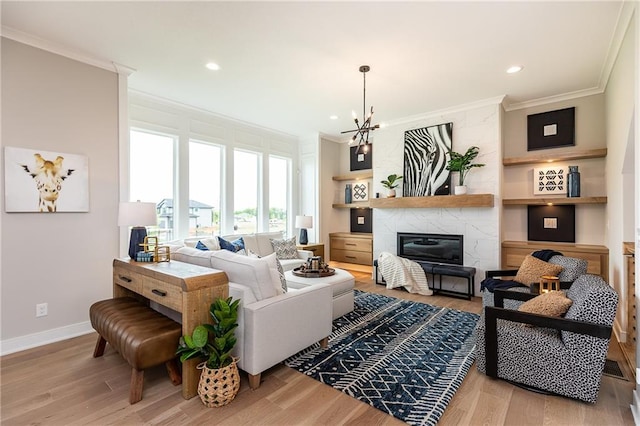 living room with ornamental molding, a chandelier, light hardwood / wood-style flooring, and a fireplace